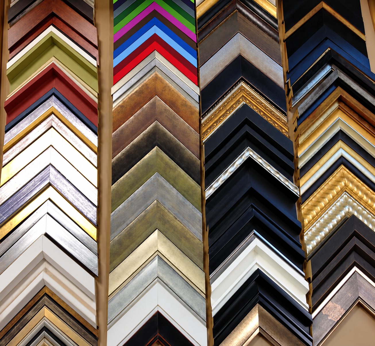 Quatre colonnes d'échantillons de baguettes d'encadrement en angle, aux finitions dorées, argentées, noires, blanches et colorées.