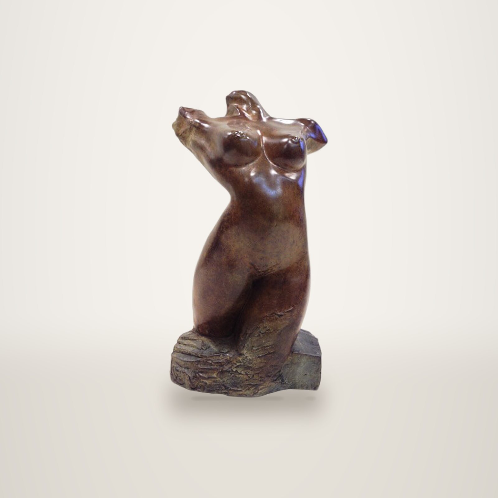 Sculpture en bronze à patine brune représentant un buste féminin cambré, posé sur un socle de pierre brute devant un mur clair.